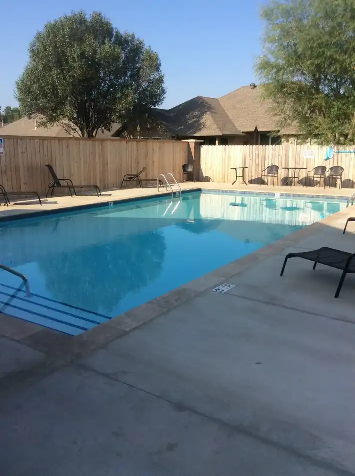 A neighbourhood HOA pool with depth markers, cedar fencing and poolside furniture