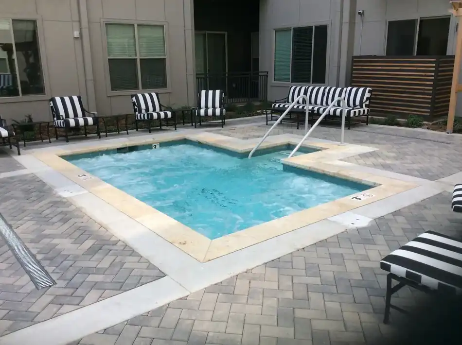 An apartment courtyard therapy spa with travertine coping and herringbone pavers