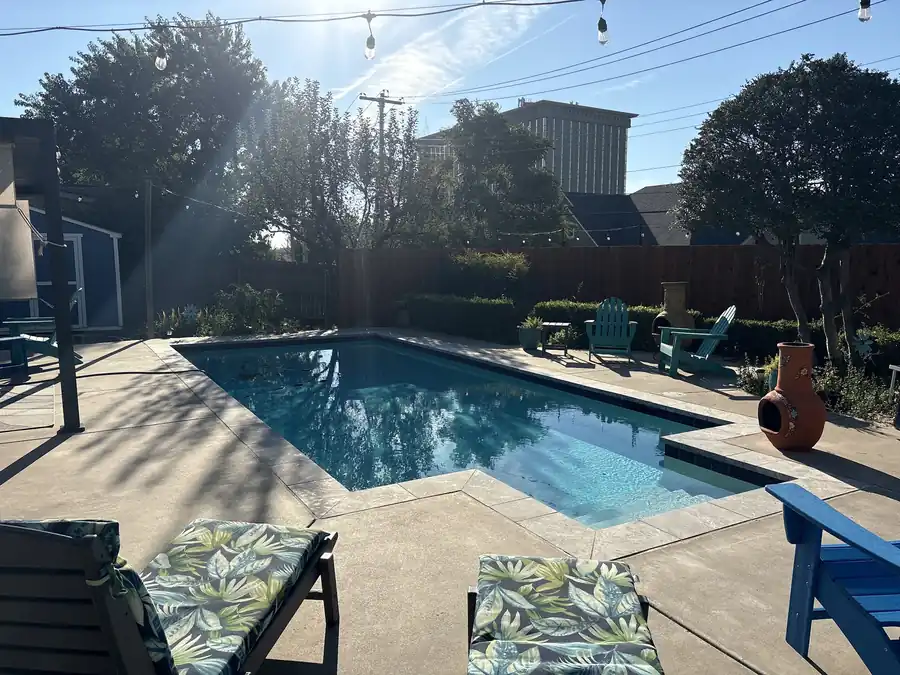 A rectangular pool with a tanning ledge, string lights and Adirondack chairs, an Oklahoma City backyard Cardinal Pools services